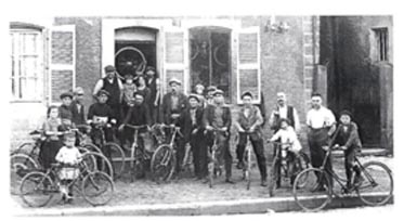 Old photograph of a group of cyclists outside a cycle shop