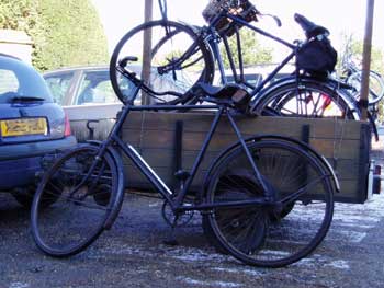 Old three wheeler in a trailer and two other cycles